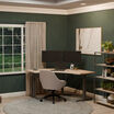 A minimalist home office featuring a light wood L-shaped standing desk with dual monitors, a laptop, and a cozy upholstered chair, set against dark green walls and a large window with garden views.